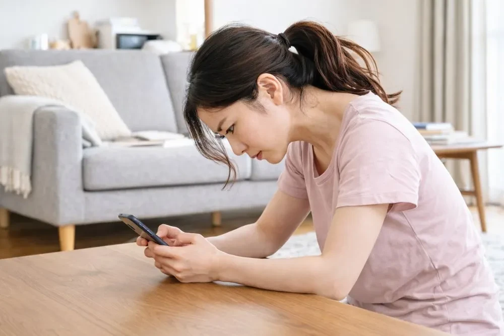 スマホ操作で首肩に負担がかかる女性