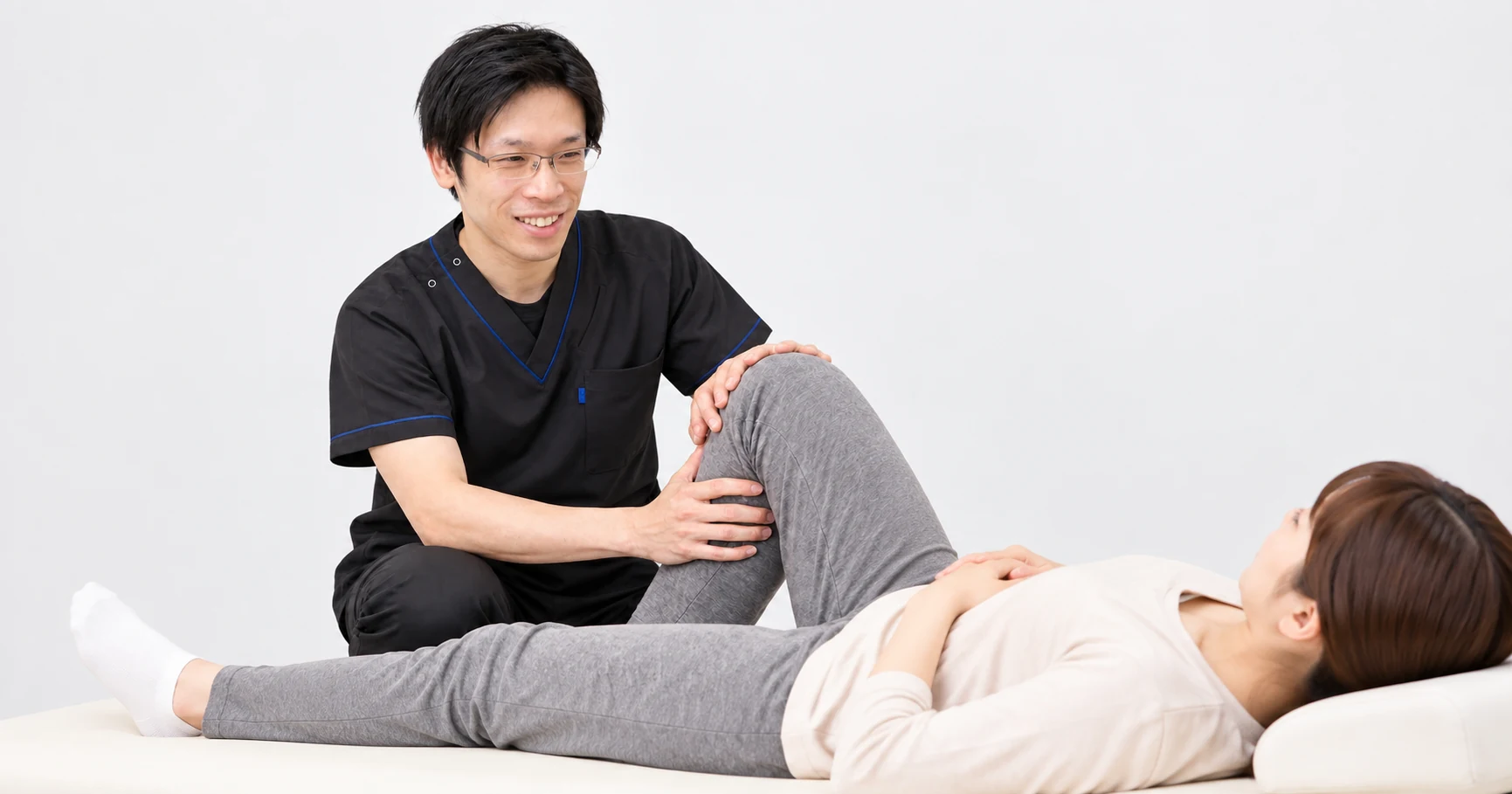 仰向けの患者様の膝を曲げ、院長が膝の動きを確認する様子